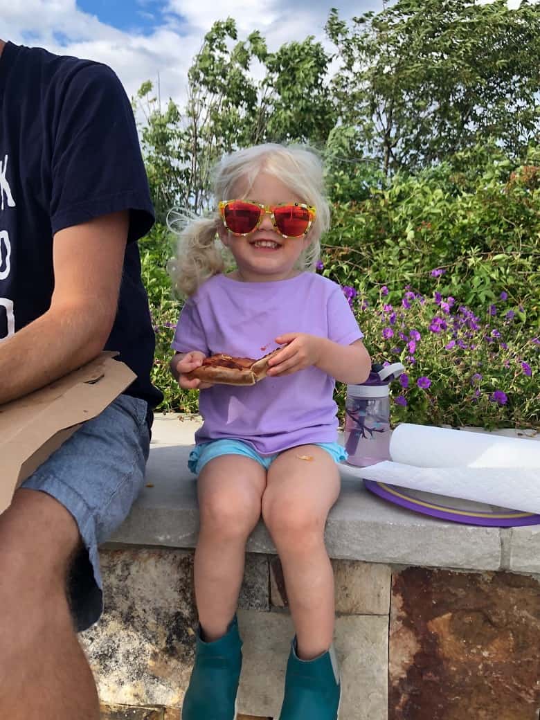toddler eating pizza with sunglasses on 