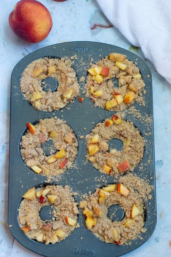healthy peach crumble donuts before baking in donut pan with peach topping