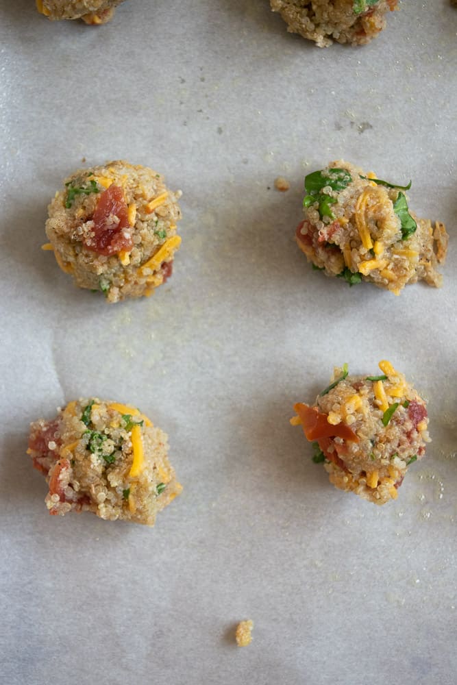 closeup of raw quinoa and meatball batter on parchment paper and baking sheet before baking