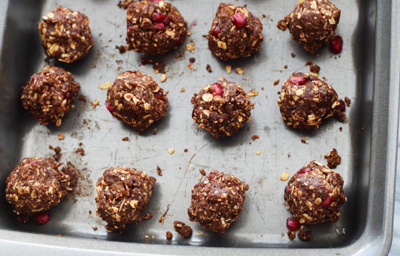 baking sheet with chocolate date oat balls with pomegranate seeds