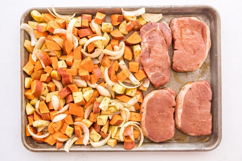 thick pork chops with fall medley of vegetables before cooking on sheet pan