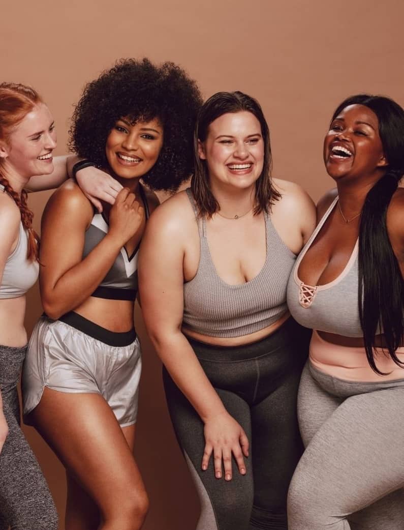 4 women huddled together of all different body sizes