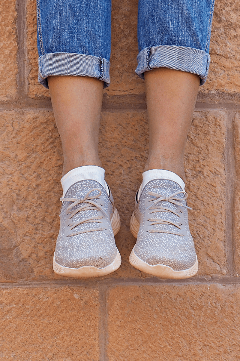 Legs and shoes hanging down off brick wall