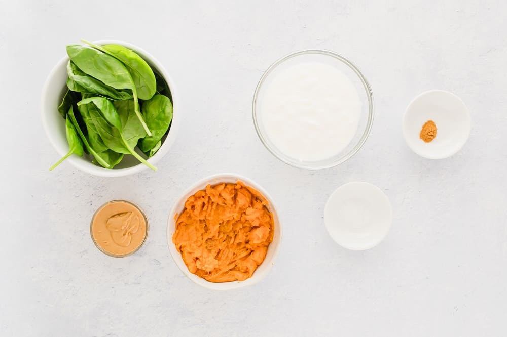 overhead view of ingredients for homemade baby food, mashed sweet potato in bowl and spinach in bowl