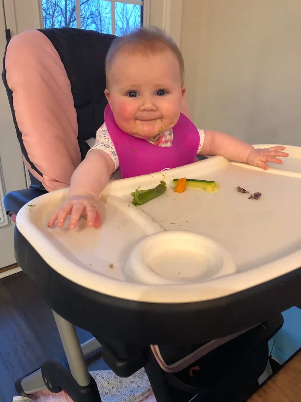 6 month old baby in high chair eating solids