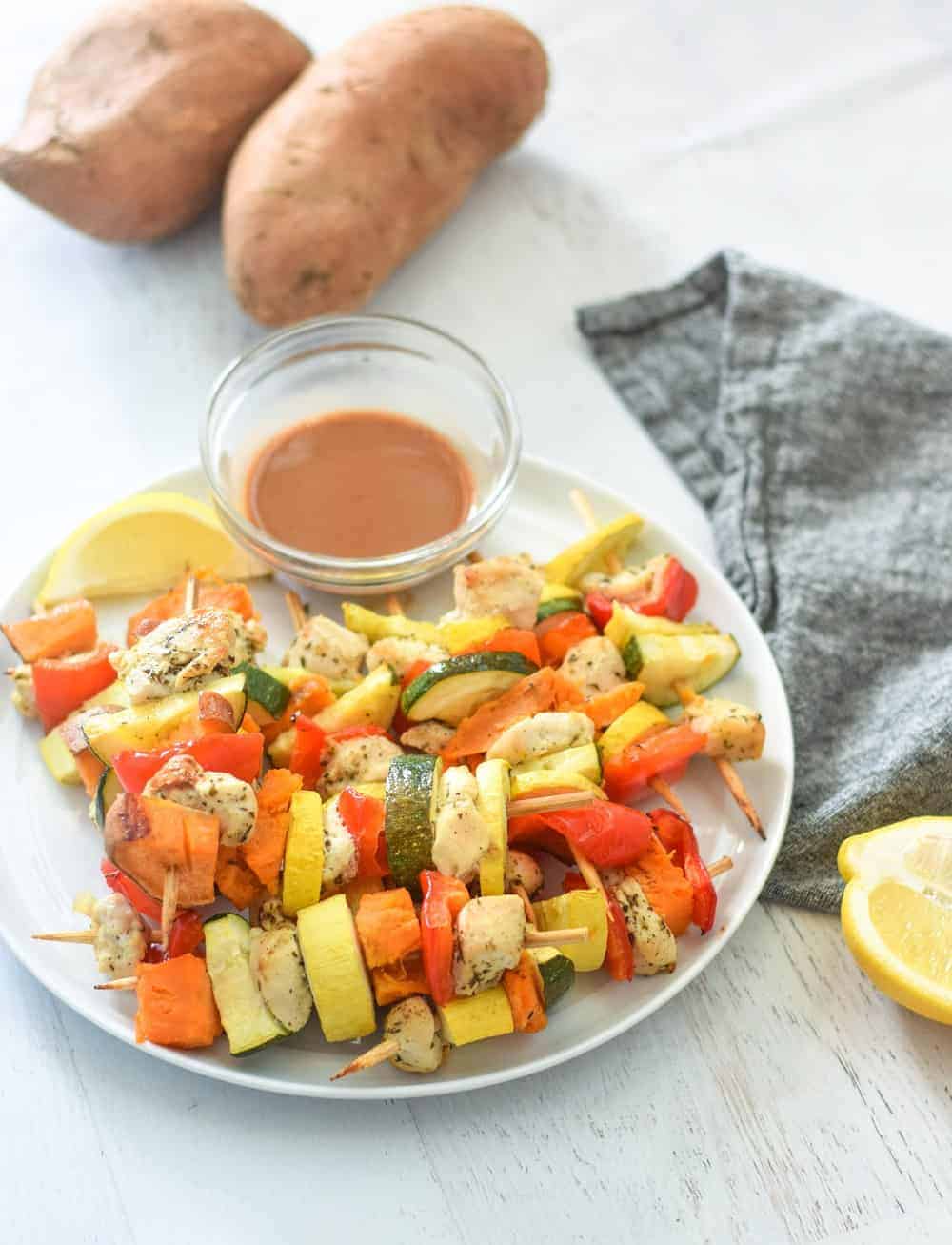white plate with easy oven baked kebabs with chicken and vegetables and creamy sauce for dipping