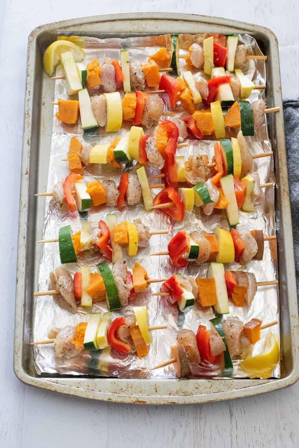 Raw chicken and veggies on skewers before making chicken kabob recipe in oven