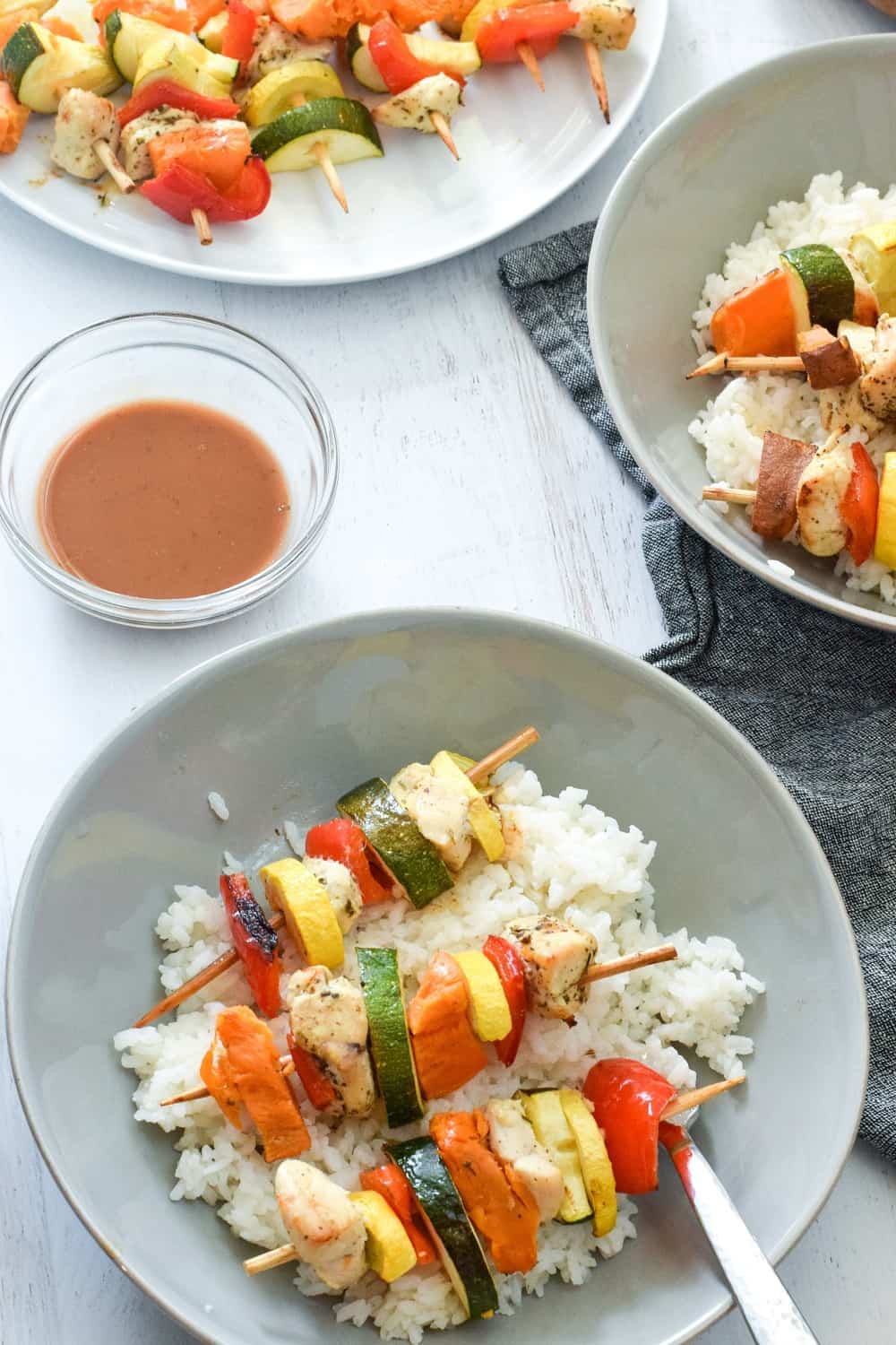 homemade chicken kebabs on white rice on gray bowl