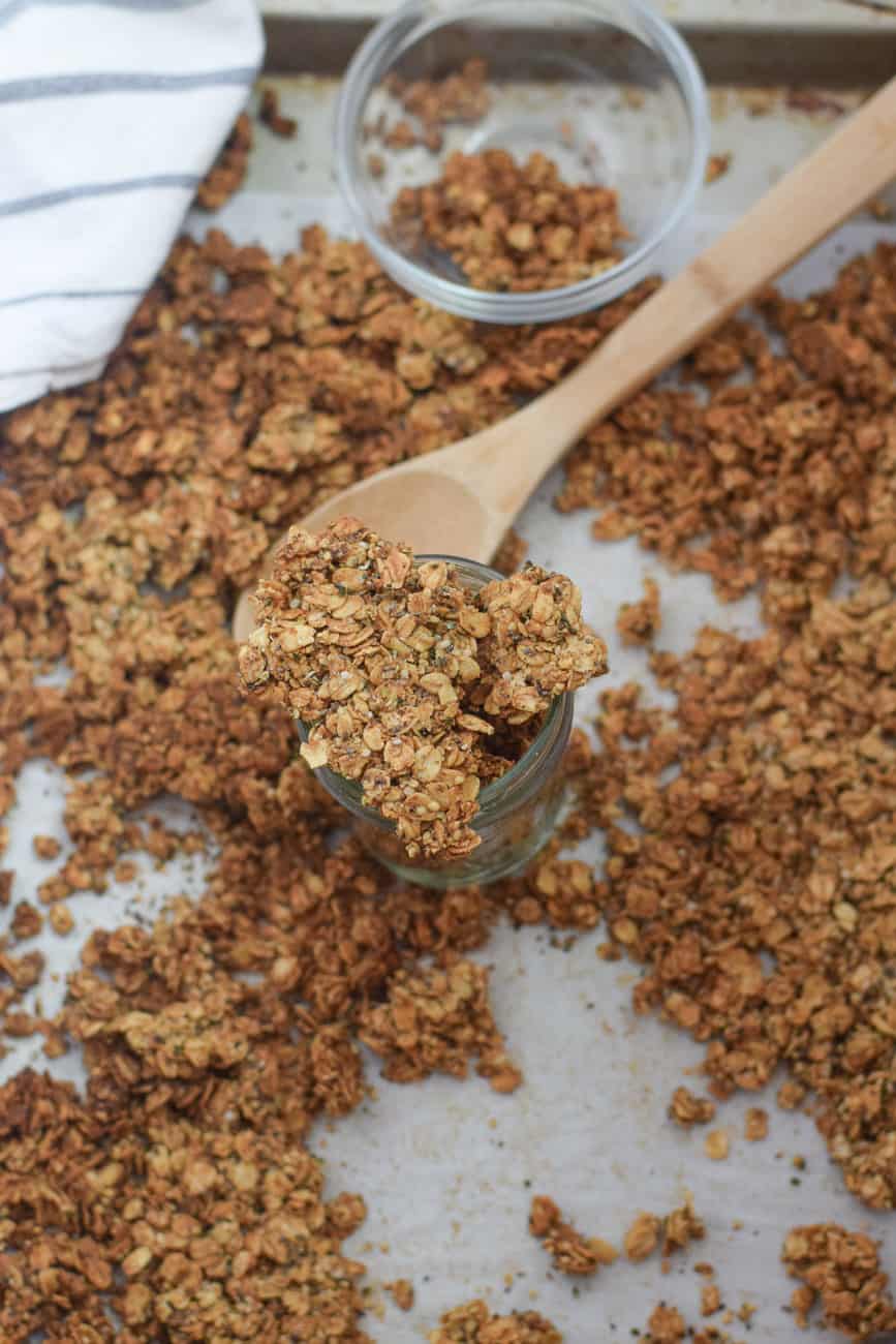 Homemade vegan granola chunks on a baking sheet with wooden spoon 