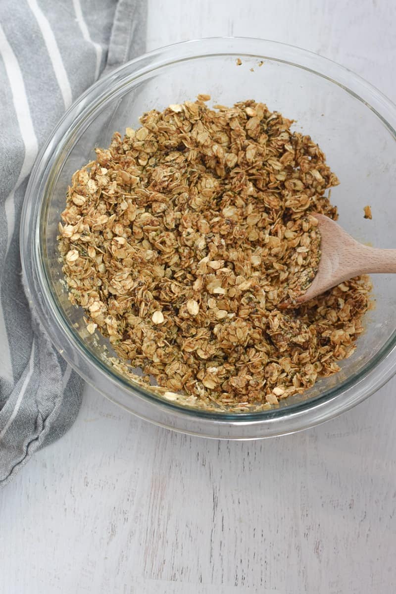 clear bowl with ingredients for hemp seed granola with wooden spoon