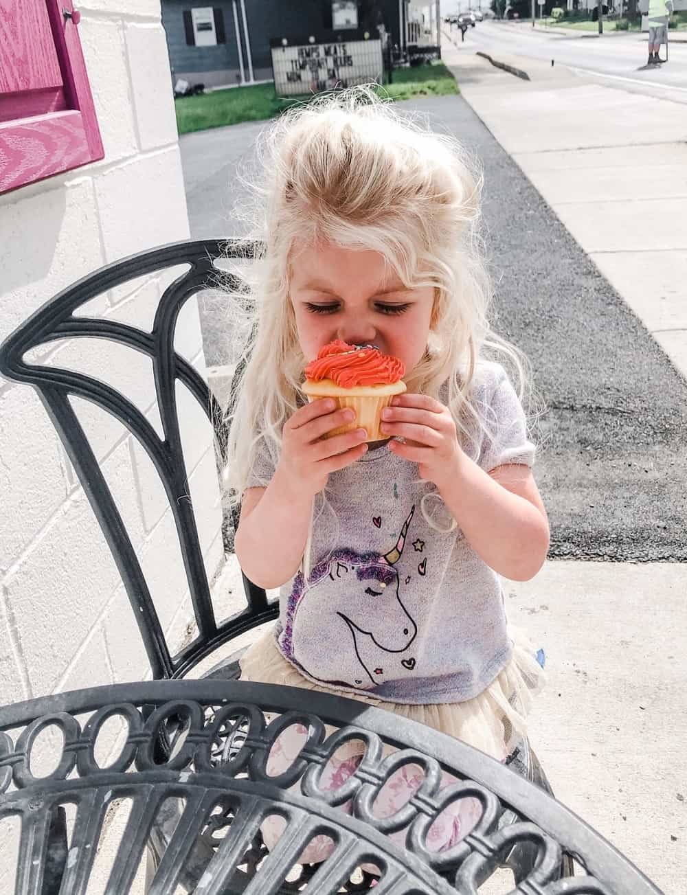 toddler eating cupcake with pink frosting
