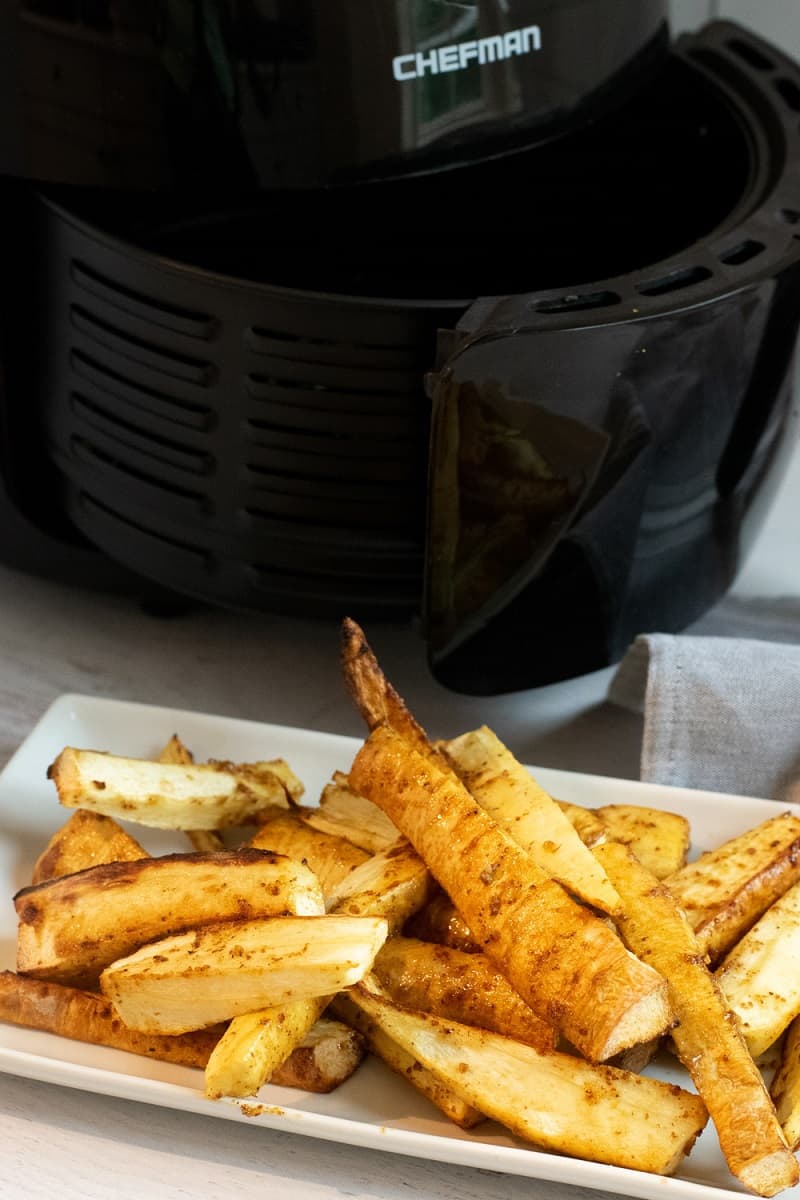 air fryer parsnip fries on white plate in front of air fryer