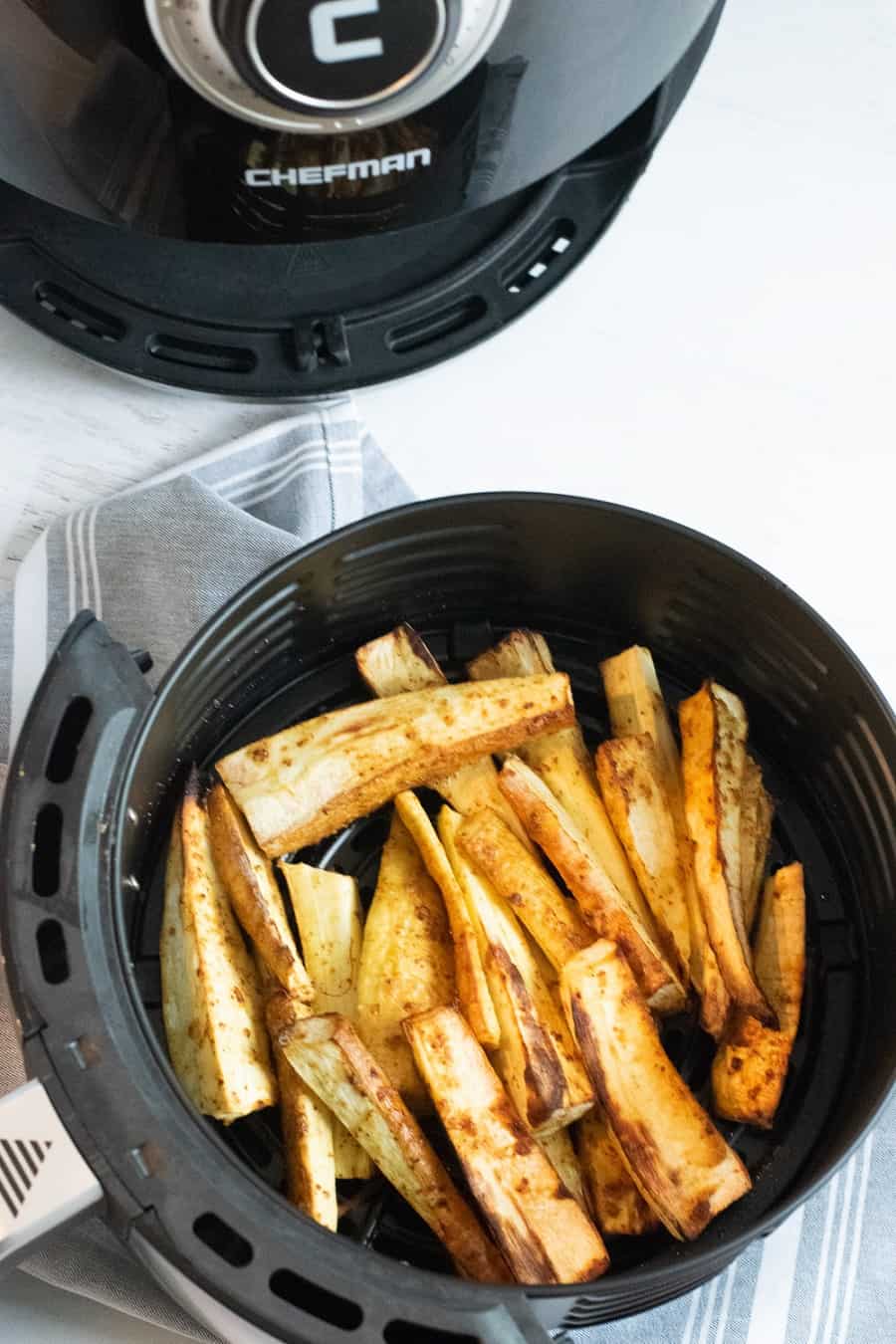 black air fryer with air fried parsnips in them 