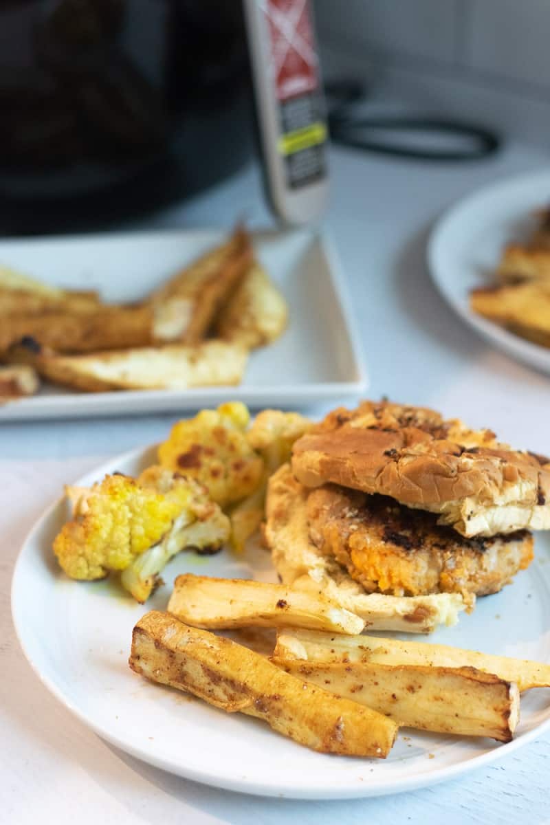 air fryer parsnip fries on white plate with cauliflower and sweet potato burger