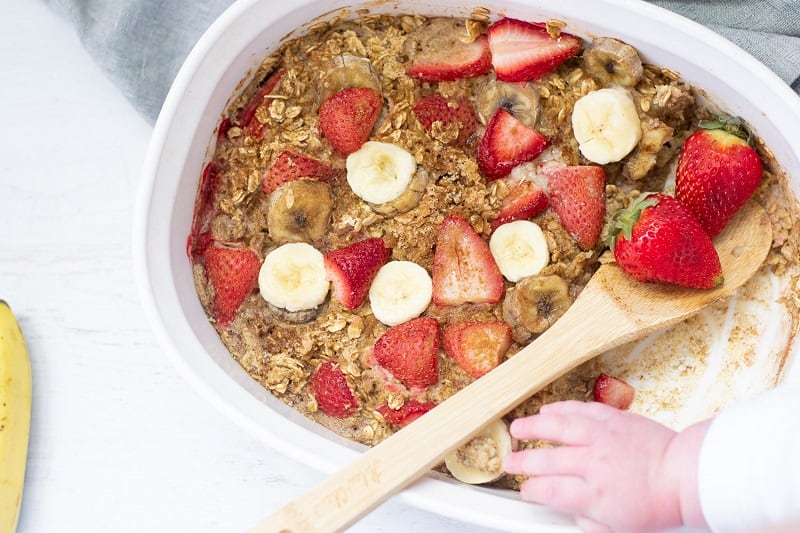 strawberry baked oatmeal with wooden spoon in white baking dis