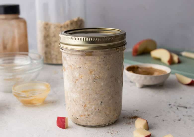 High protein overnight oats in mason jar with cover on top and apples in background